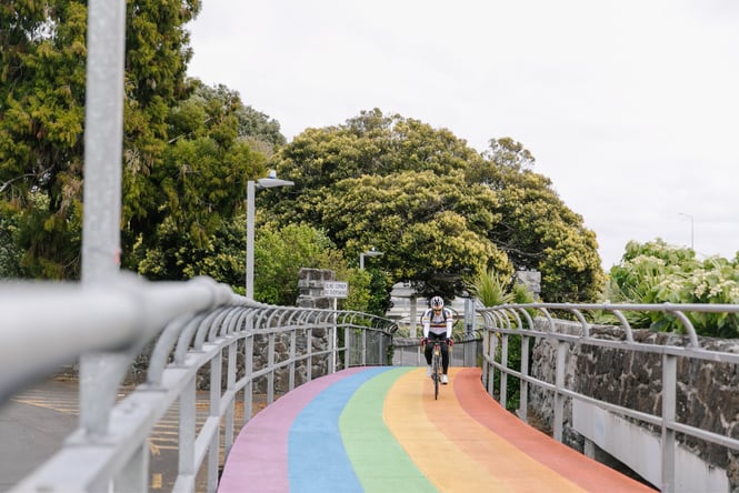 A cyclist biking along a rainbow bridge.