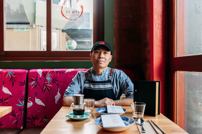 Le Minh the owner of Apache sitting at a table in the restaurant.