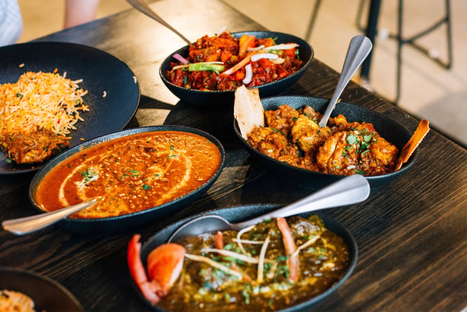 A close up of lots of bowls of curry on a table.