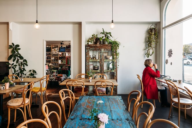 The interior of Squirrel with a woman drinking a coffee in a seat at the window.