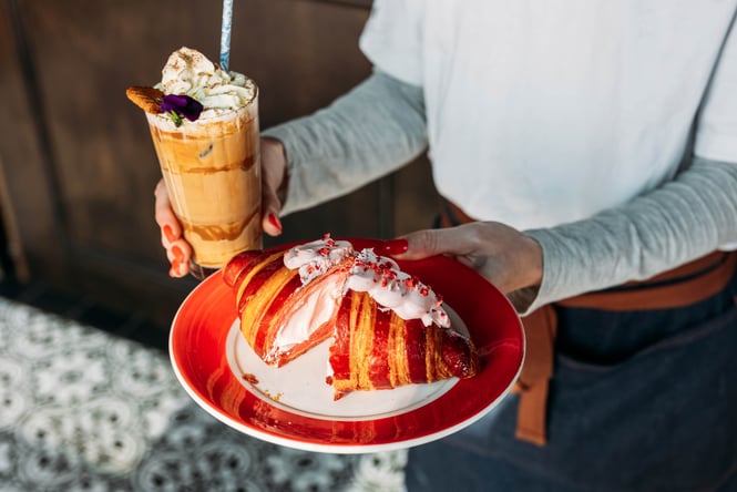 Waiter delivering an iced drink and strawberry croissant.