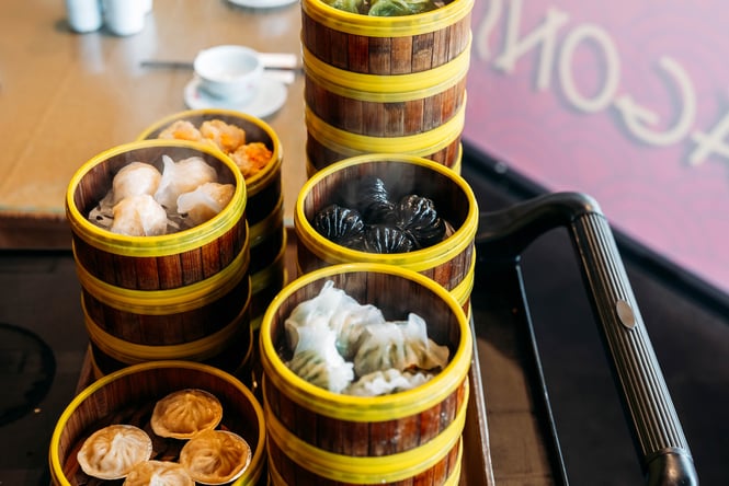 Stacks of bamboo steamers holding dumplings and other yum cha items.