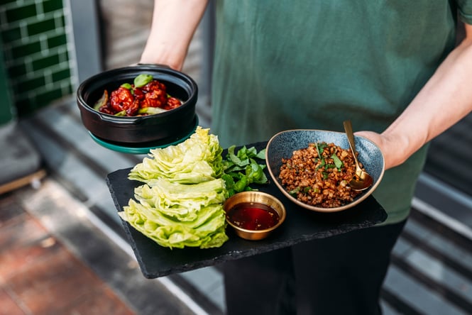 Waiter serving plates of food to customers.