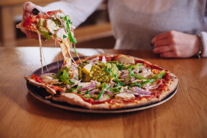 A hand holding a slice of pizza.