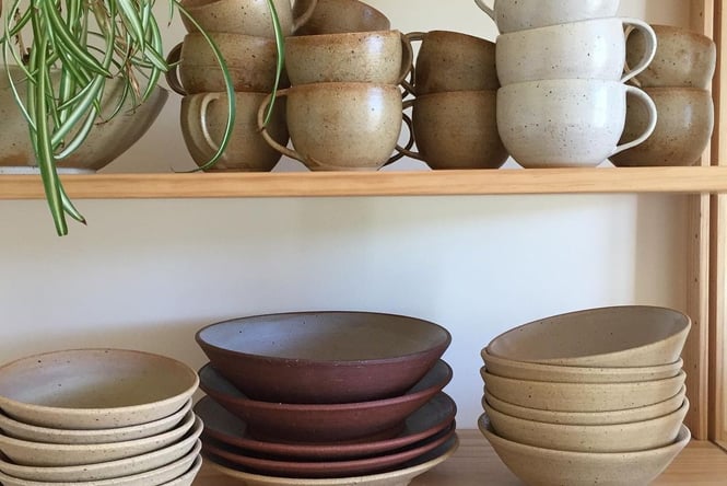 Stacked ceramic cups and plates on a shelf.