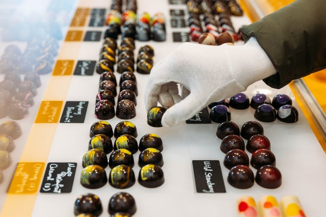 Shop assistant putting out chocolates in a cabinet in Bamboo Sweets on Casabella Lane.