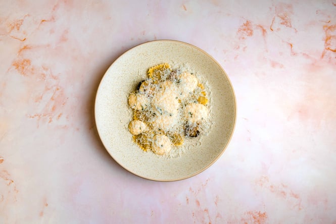 A plate of pasta on a peach and white marble bench.