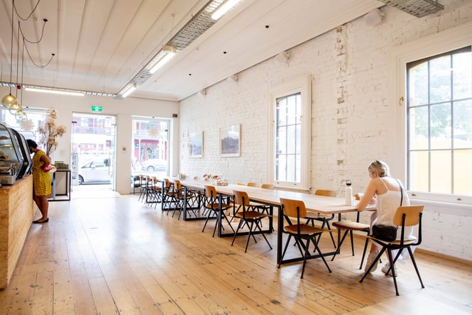 A customer sitting on her own at a very long table inside Daily Bread.