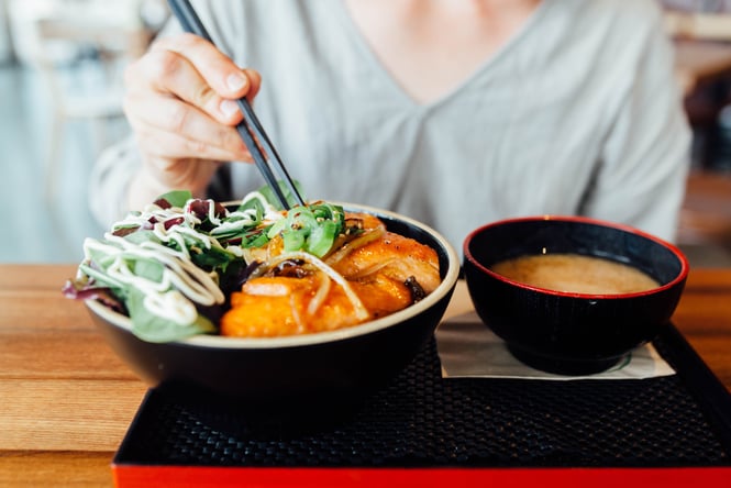 Chopsticks poking into a Japanese bowl of noodles.
