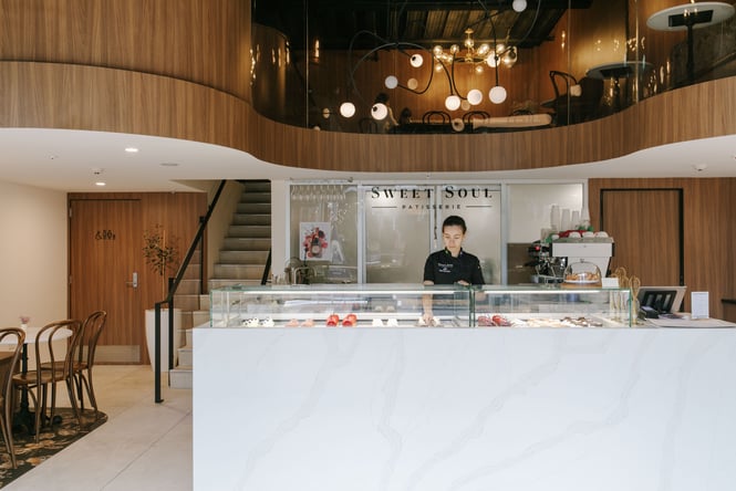 A staff member working behind a large marble bench inside a cafe.