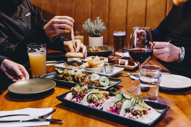 A close of burgers, fried chicken and beers on a table.