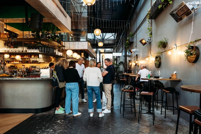 People standing and talking in a busy cafe environment.