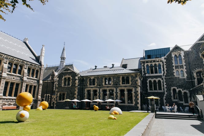 Round yellow and white sculptures on the grass within the walls of the Christchurch Arts Centre.
