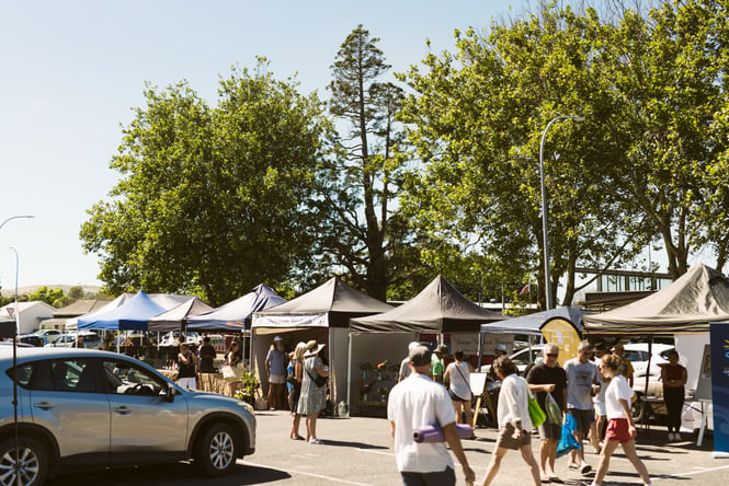 Customers walking among stalls at the Gisborne Farmers' Market.