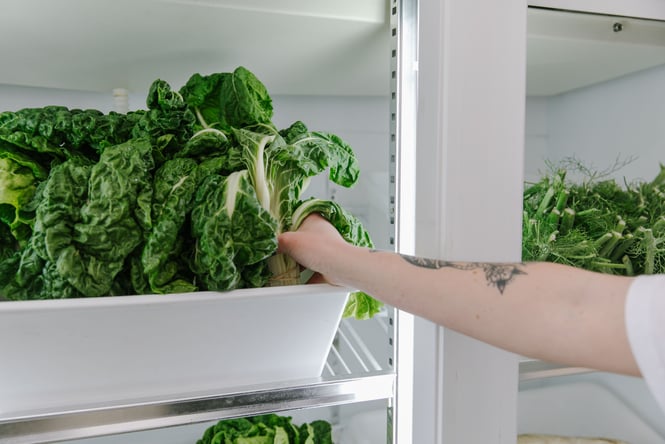 Customer pulling silverbeet out of the fridge.