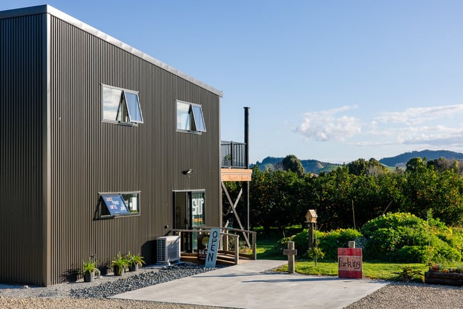 Black building exterior of farm shop with the orchard in the background.