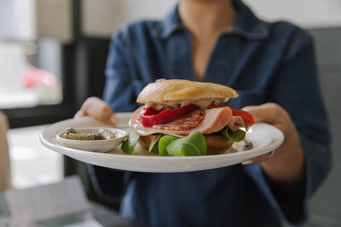 Customer holding a plate with a filled bagel at Ozone Coffee Walker Street.