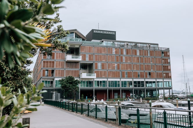 Exterior of Park Hyatt hotel building in Auckland with wharf full of parked boats in front