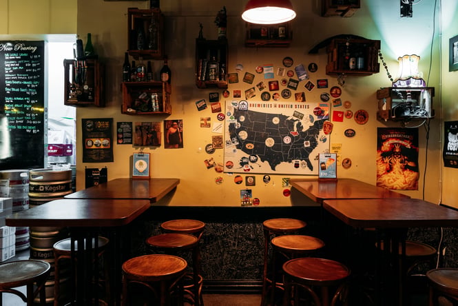 Wooden tables and chairs inside a dimly lit restaurant painted yellow.