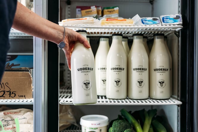 Customer selecting a bottle of milk from the fridge.
