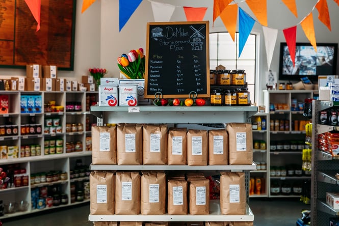 Rows of flour displayed on shelves in the shop at De Molen.
