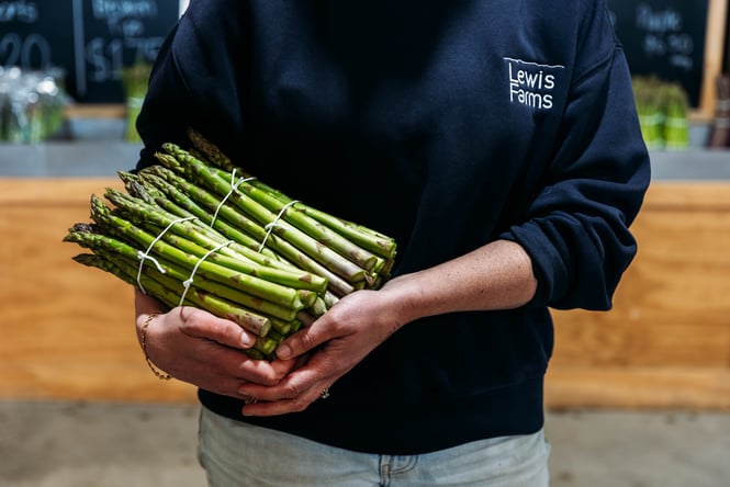Staff member holding a bunch of asparagus at Lewis Farms.