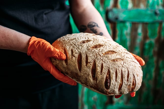 Person holding a loaf of sourdough bread.