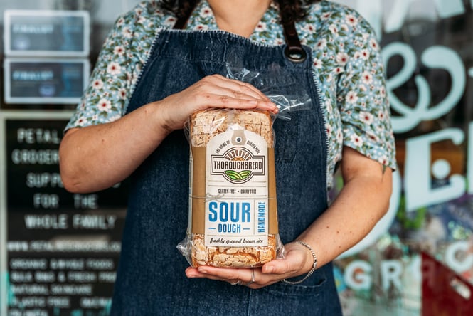 Woman holding a loaf of Thoroughbread sourdough.