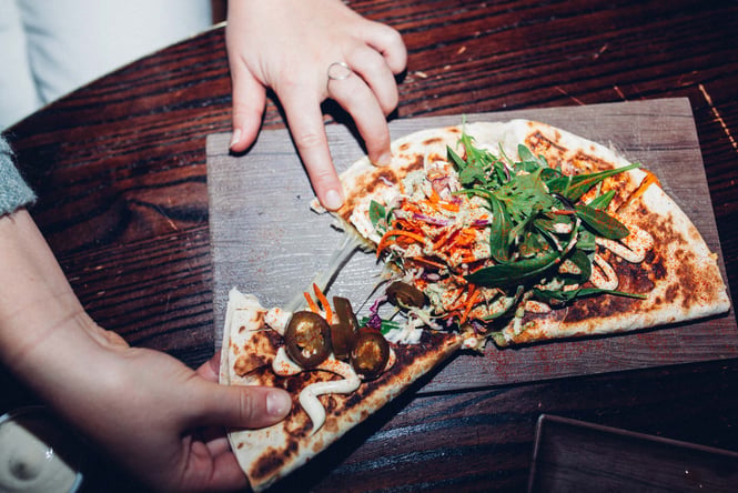 Hands pulling apart a quesadilla.