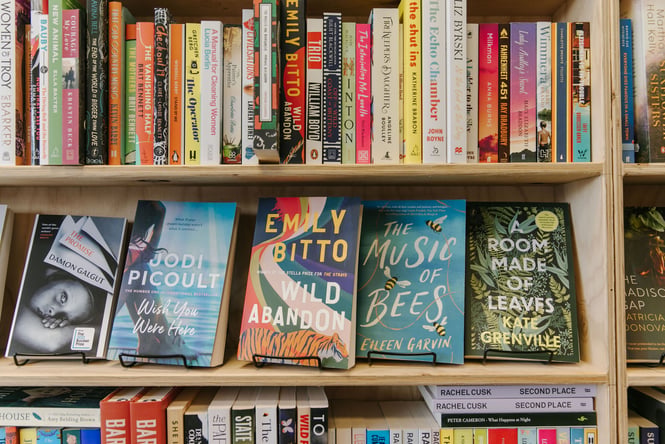 Books lined up on wooden shelves.