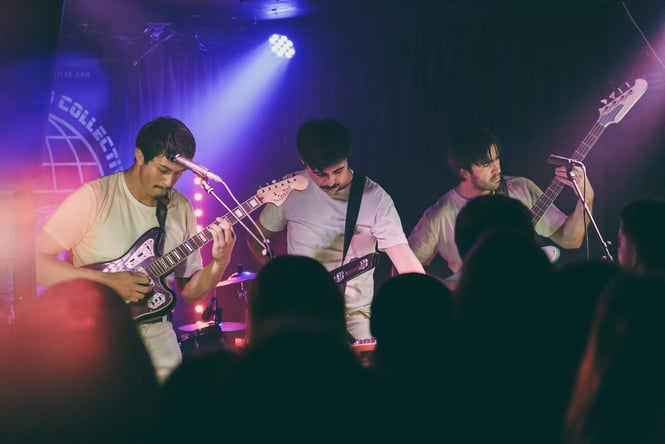 Three men playing guitars on stage.