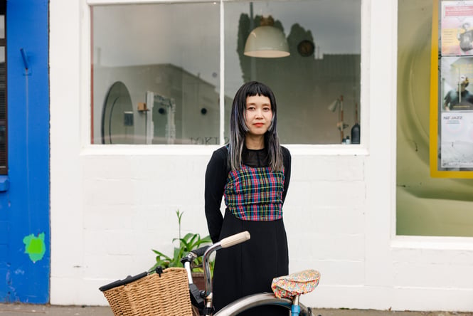 A woman looking at the camera next to a white building.