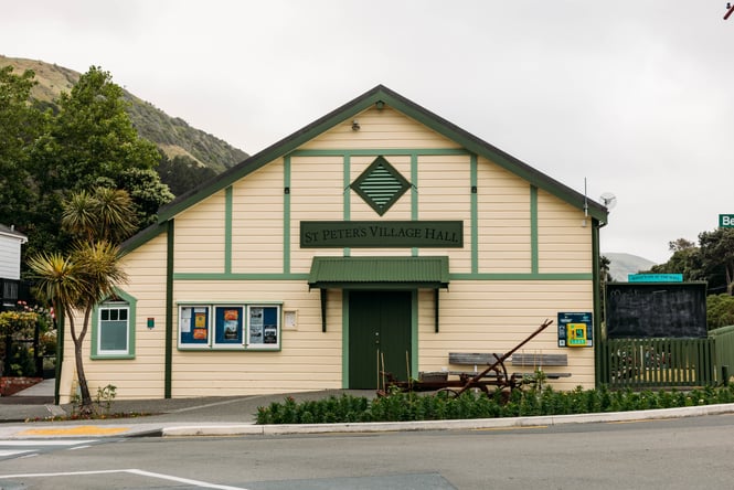 The exterior of an old cream weatherboard building with green trim.