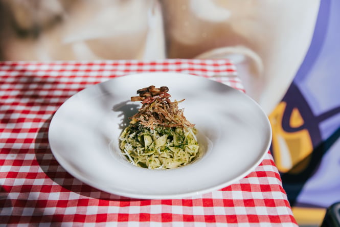 A close up of a plate of pasta on a red and white checkered table cloth.