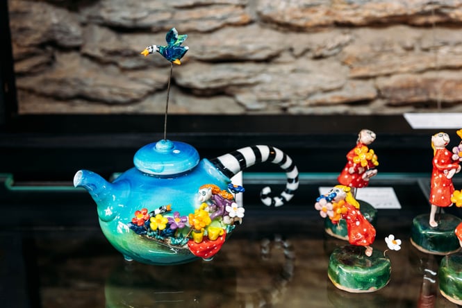 A colourful tea pot on display on a shelf.