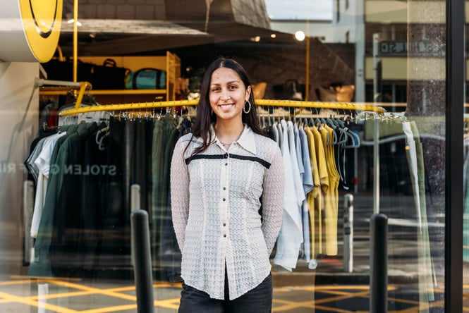 A woman smiling to camera standing outside a store.
