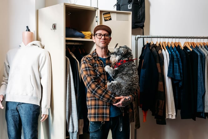 A man holding a dog looking to camera.
