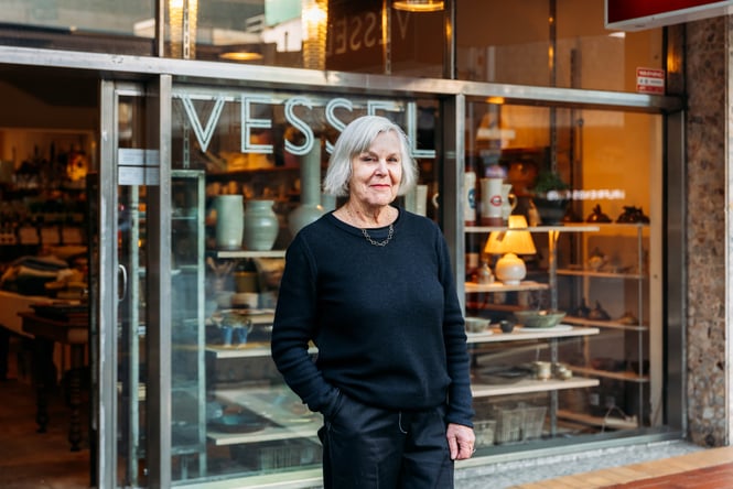A woman wearing black standing outside a retail store.