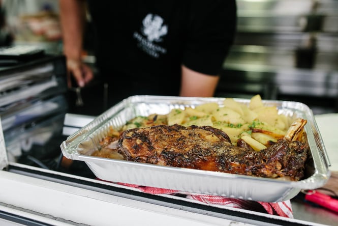 A tinfoil tray of cooked lamb and potatoes.