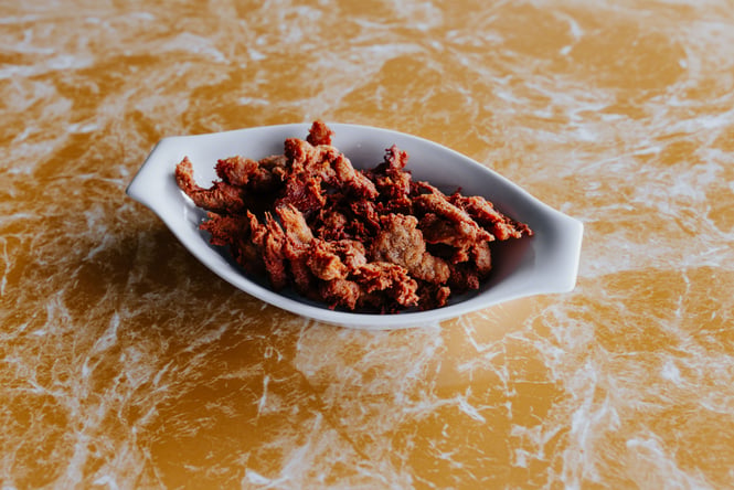 A flat of pretend fried chicken on a yellow and white table.