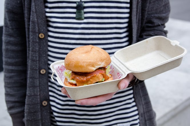 A person holding a burger in a box.