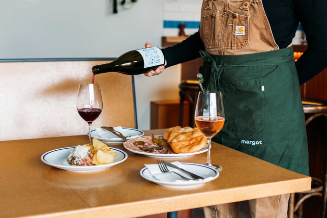 Wine being poured into glasses by a staff member.