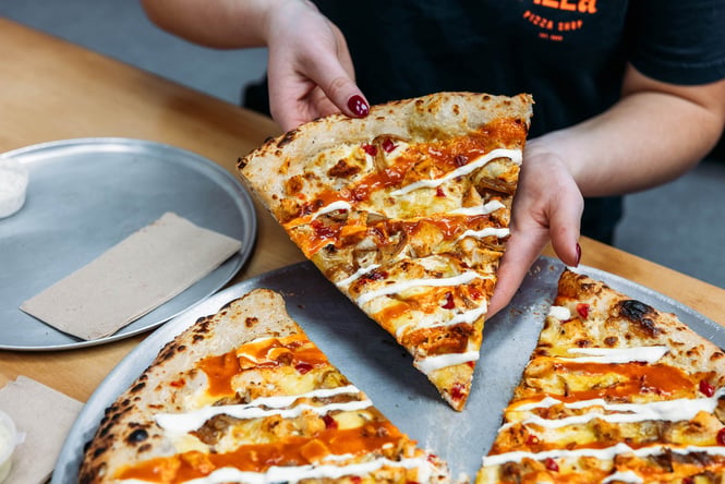 Someone picking up a big slice of pizza at Tony's in Palmerston North
