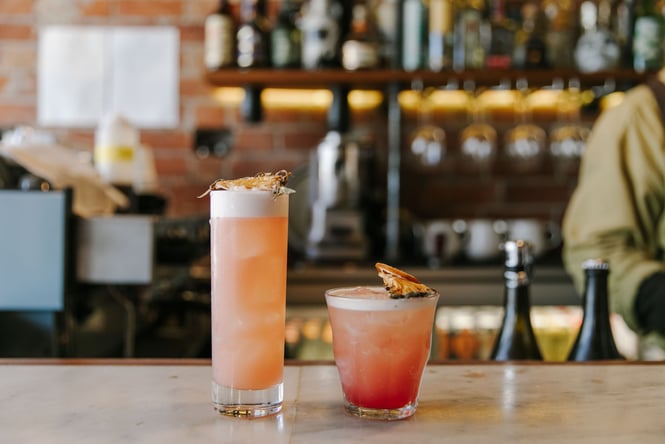 A short and tall peach coloured cocktail sitting on the bar at Civil and Naval
