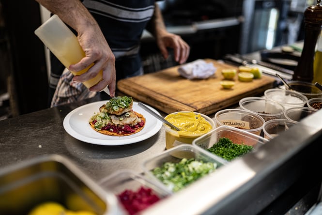 A chef making an open taco in a kitchen.