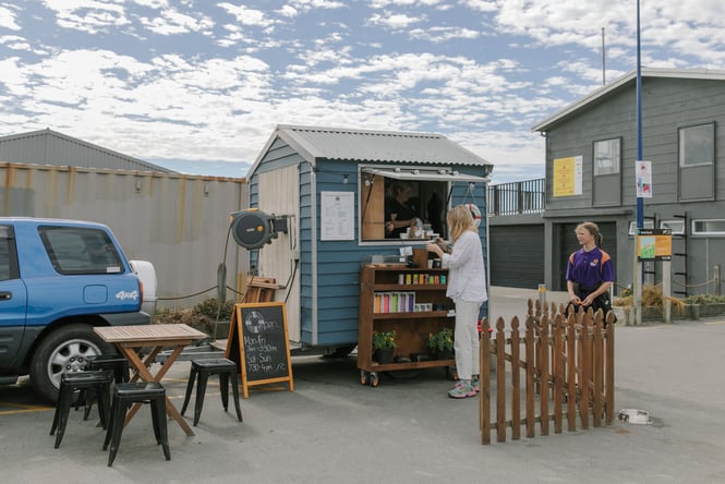 A woman ordering coffee from a small coffee shack at the beach.