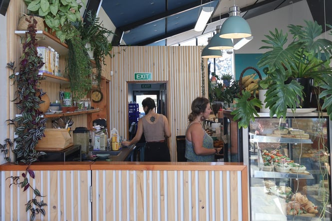 Two women working behind the counter at a cafe.