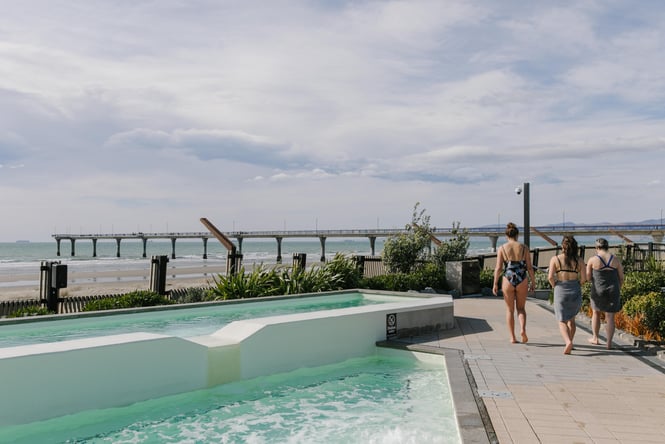 Three women walking alongside a pool.