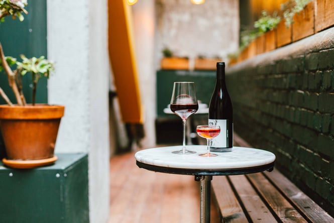 A bottle and glasses of wine on an outdoor table.