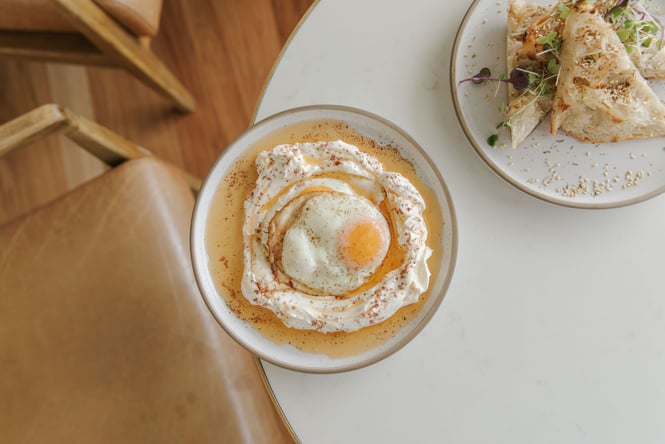 Flat lay of Turkish eggs next to plate of toasted focaccia
